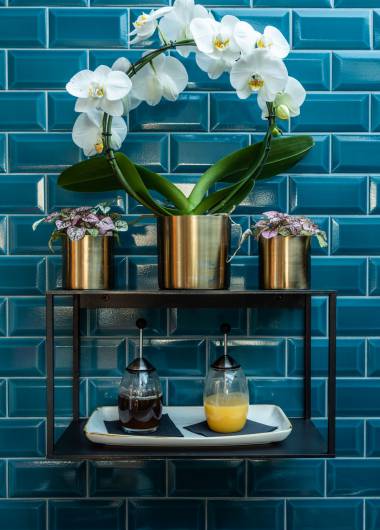 Golden flower pots with orchids in front of blue tiles