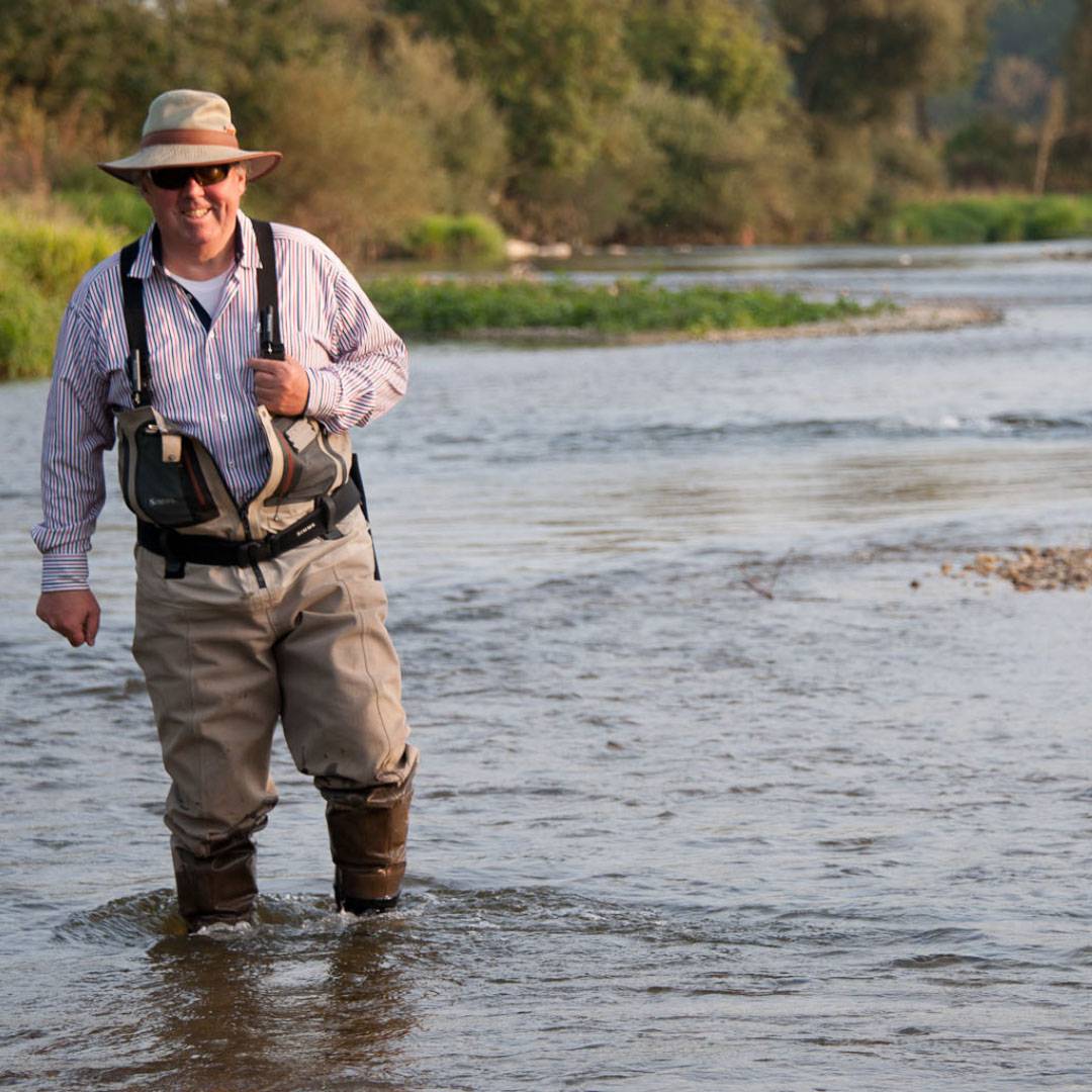 fisherman standing in a river smiling passionately