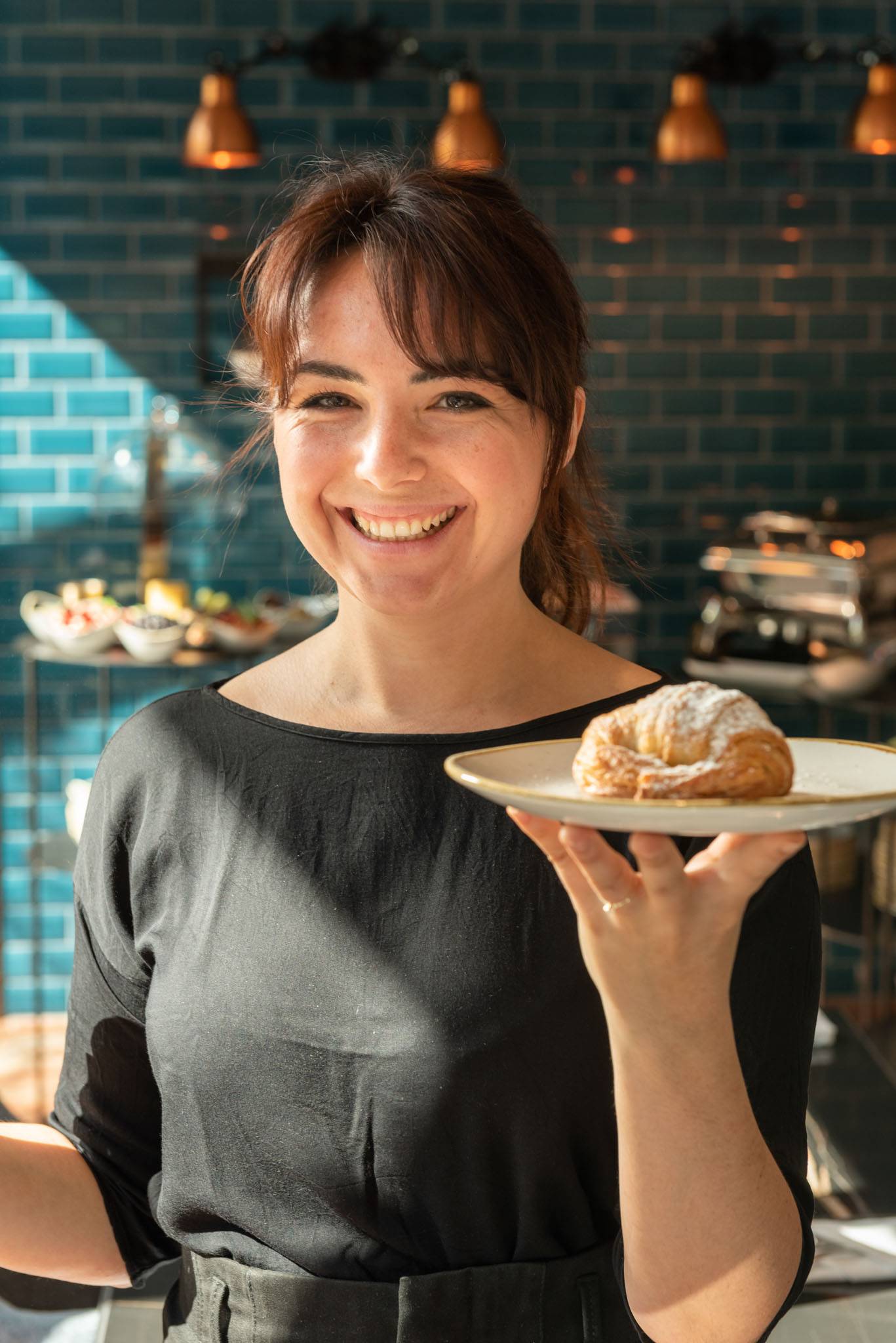 Kellnerin hält Teller mit Croissant 