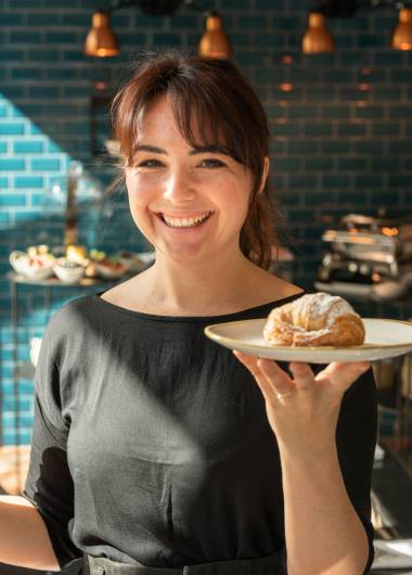 Kellnerin hält Teller mit Croissant