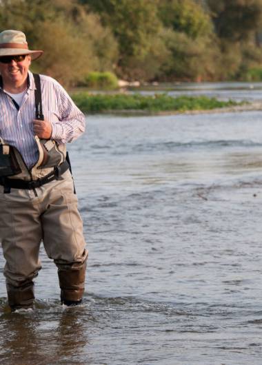 fisherman standing in a river smiling passionately