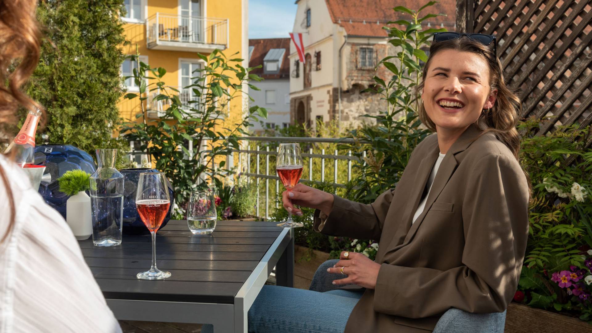 Frau lächelt und hält dabei ein Glas Wein